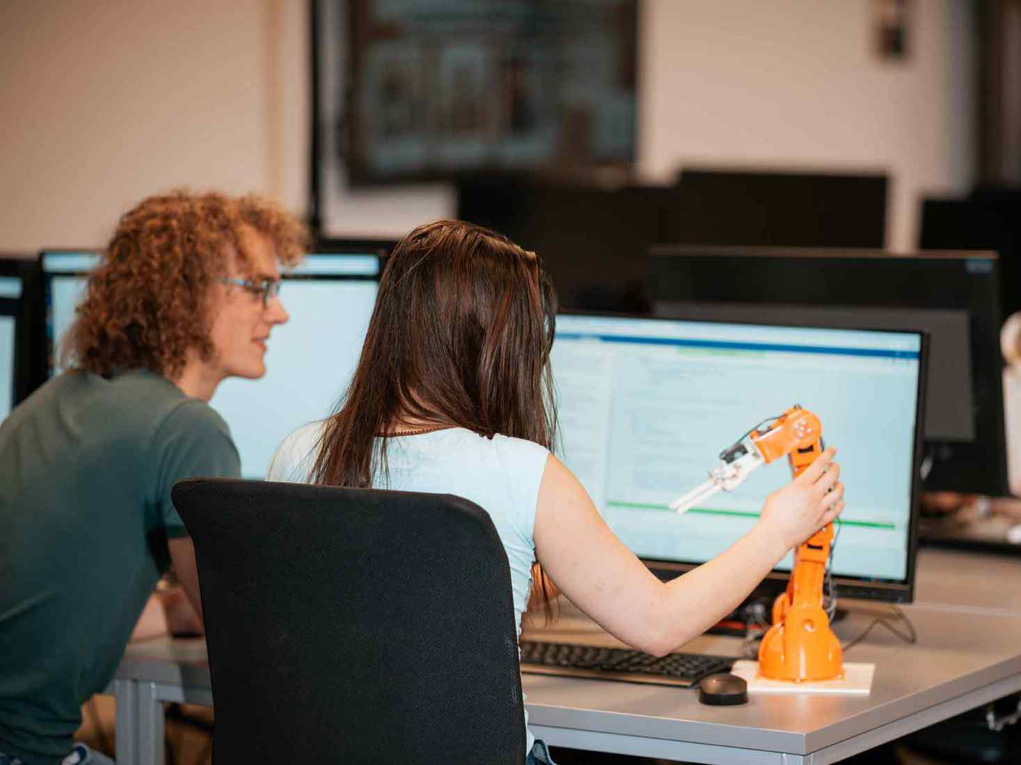 Two students working together to code movements of a robot. 