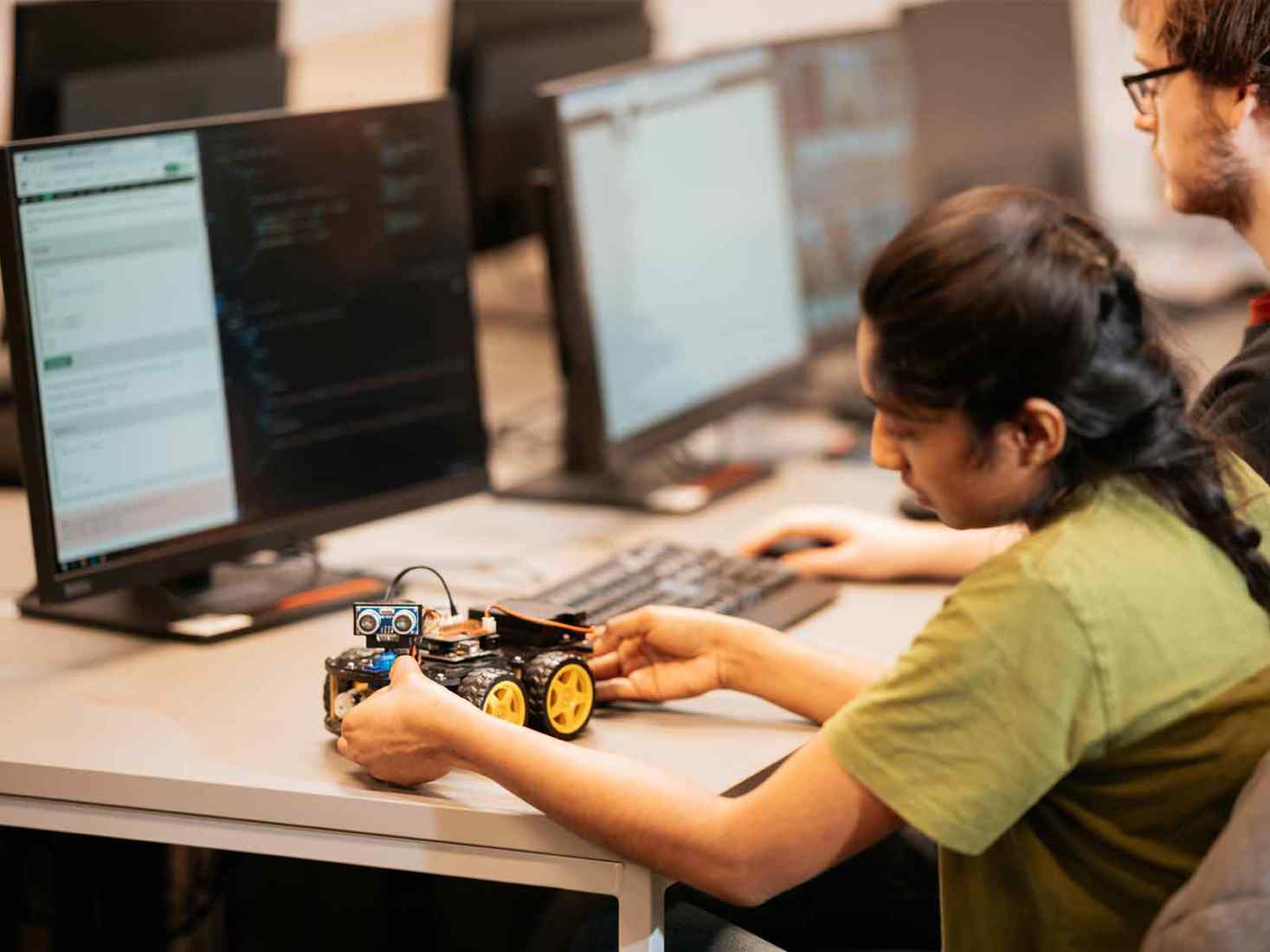 A student working on a small wheeled robot. 