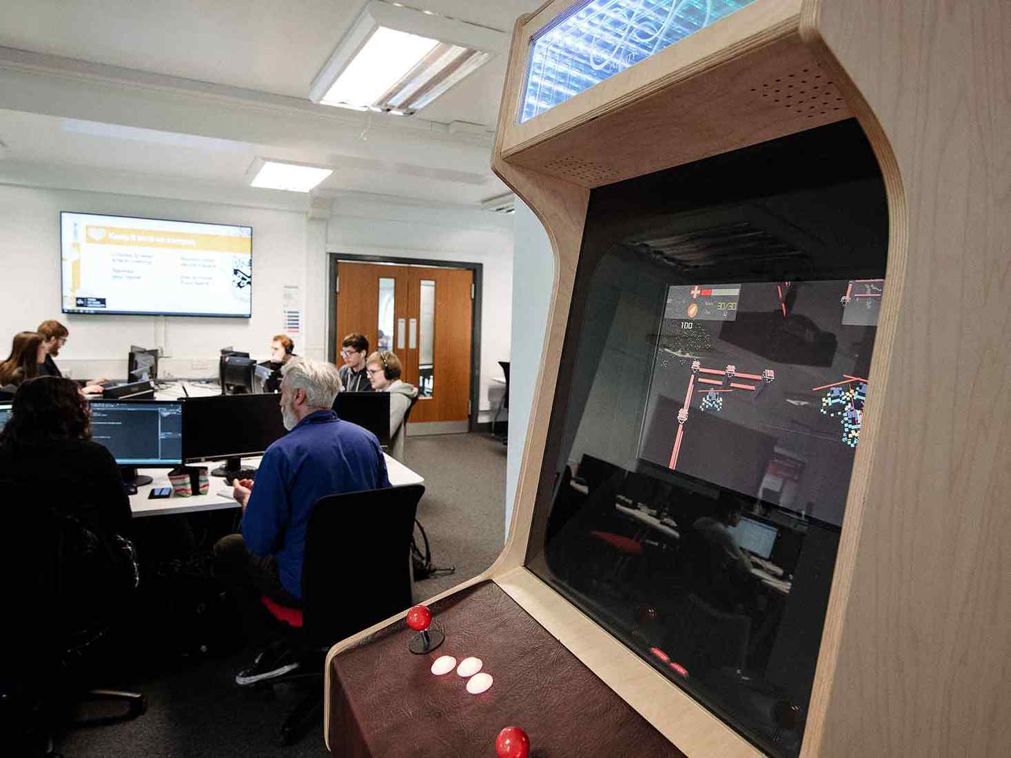 An arcade game in a classroom full of people 