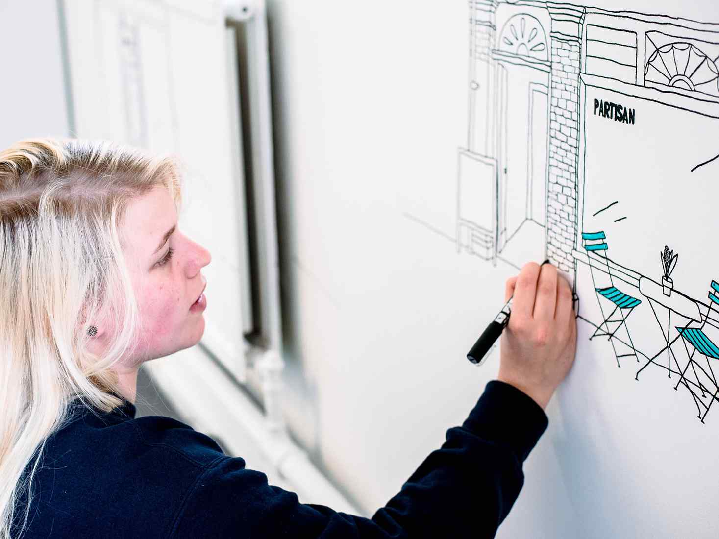 Student sketching on paper on wall 