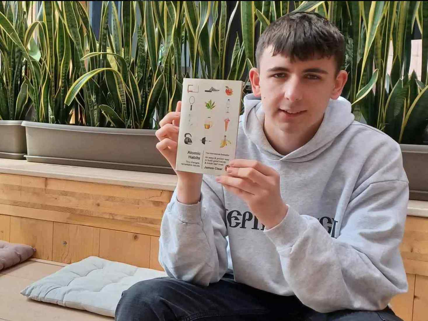 A student holds up a book cover design 