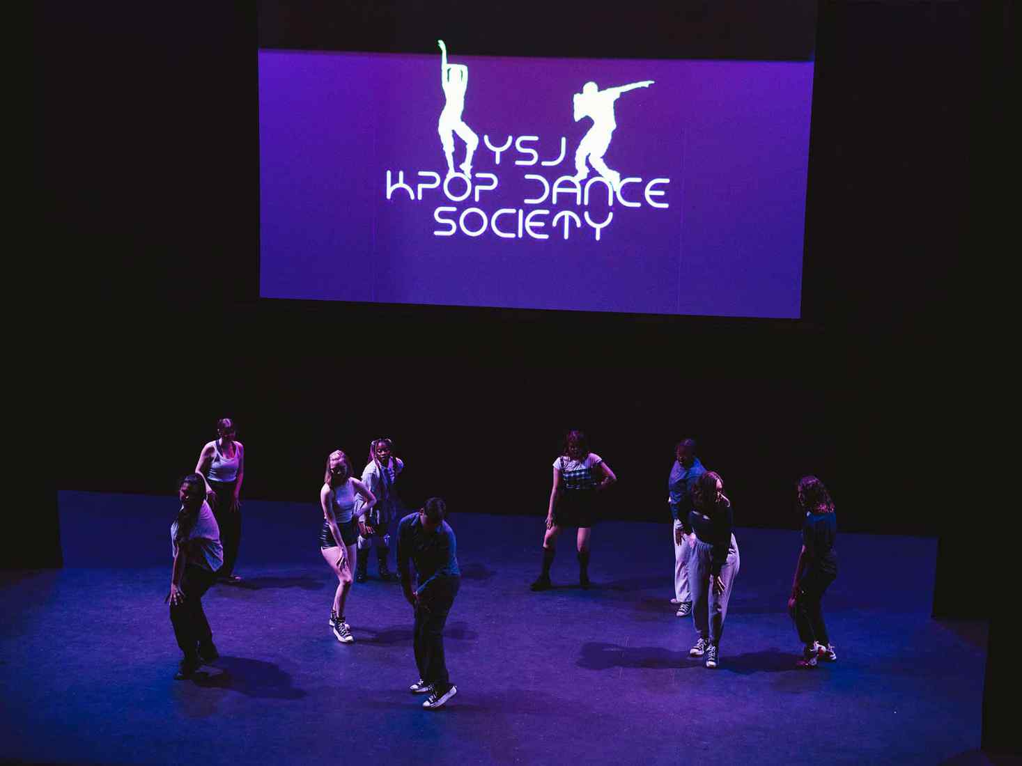 Group of students performing a kpop dance on stage. 