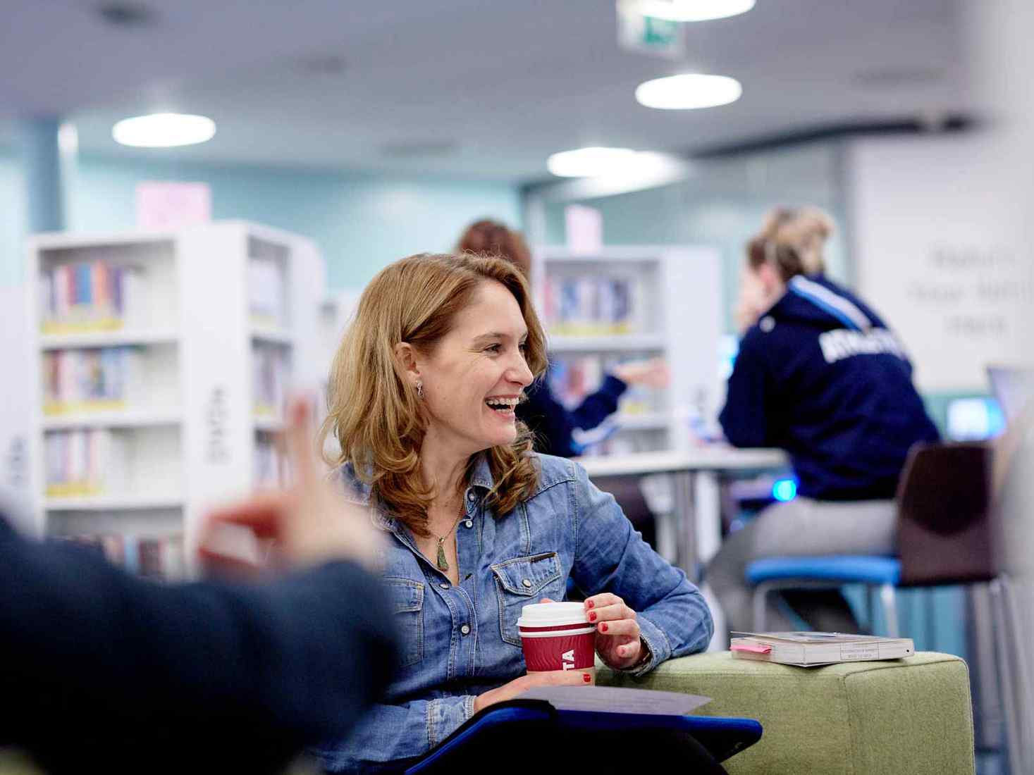 A mature student talks to fellow students in the York St John library. 