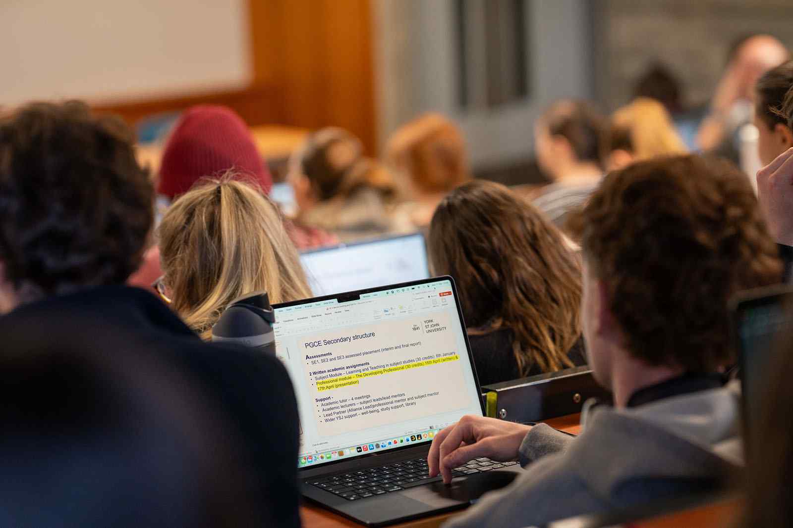Student sitting in lecture theatre using laptop 
