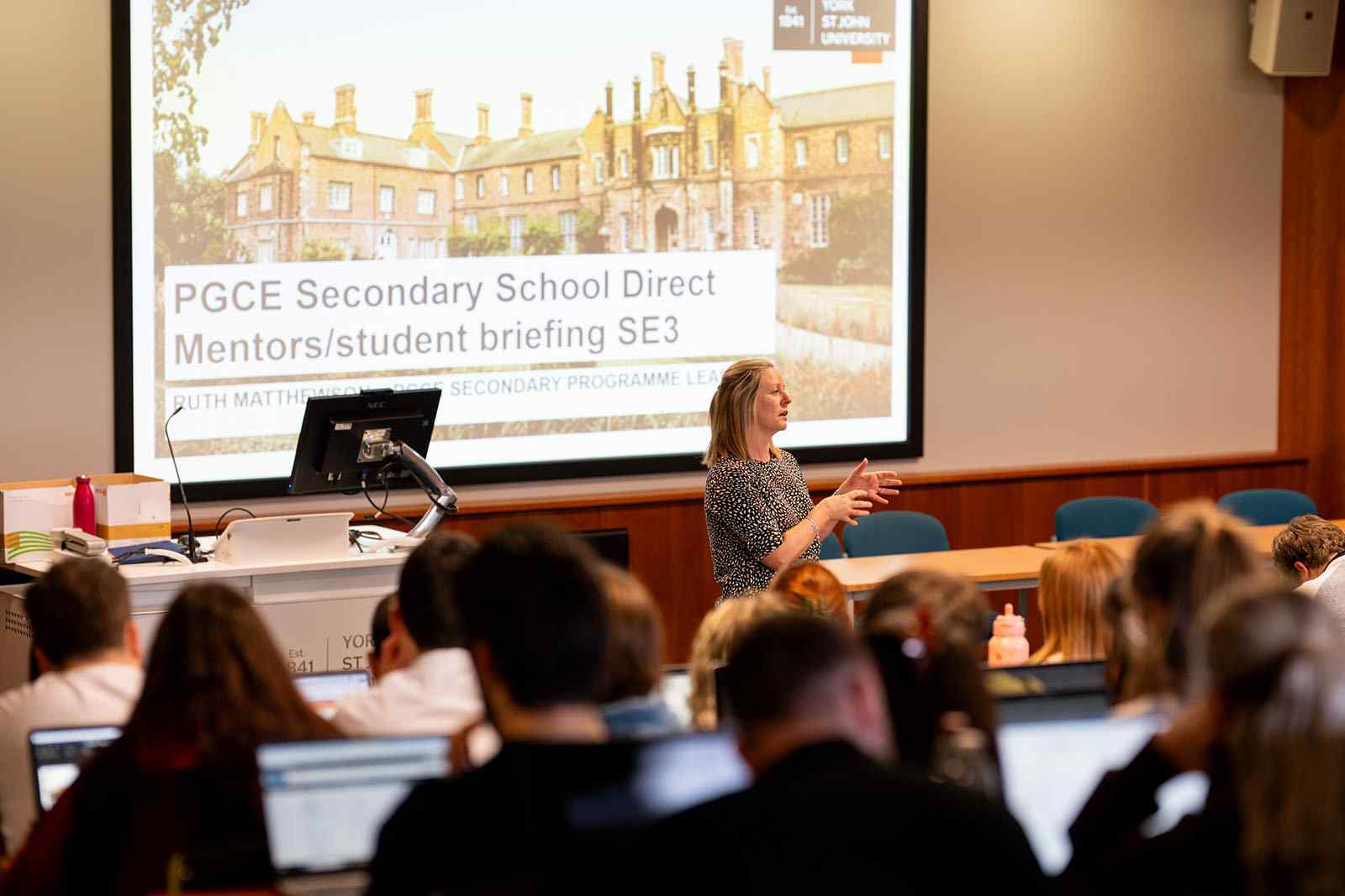 PGCE lecture, blonde female lecturer talking to students in lecture theatre 