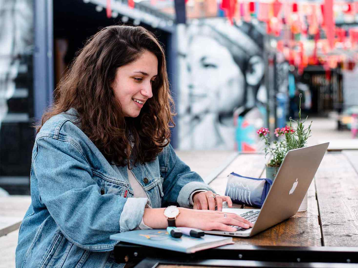 Student working on a laptop, in front of a mural at Spark York. 