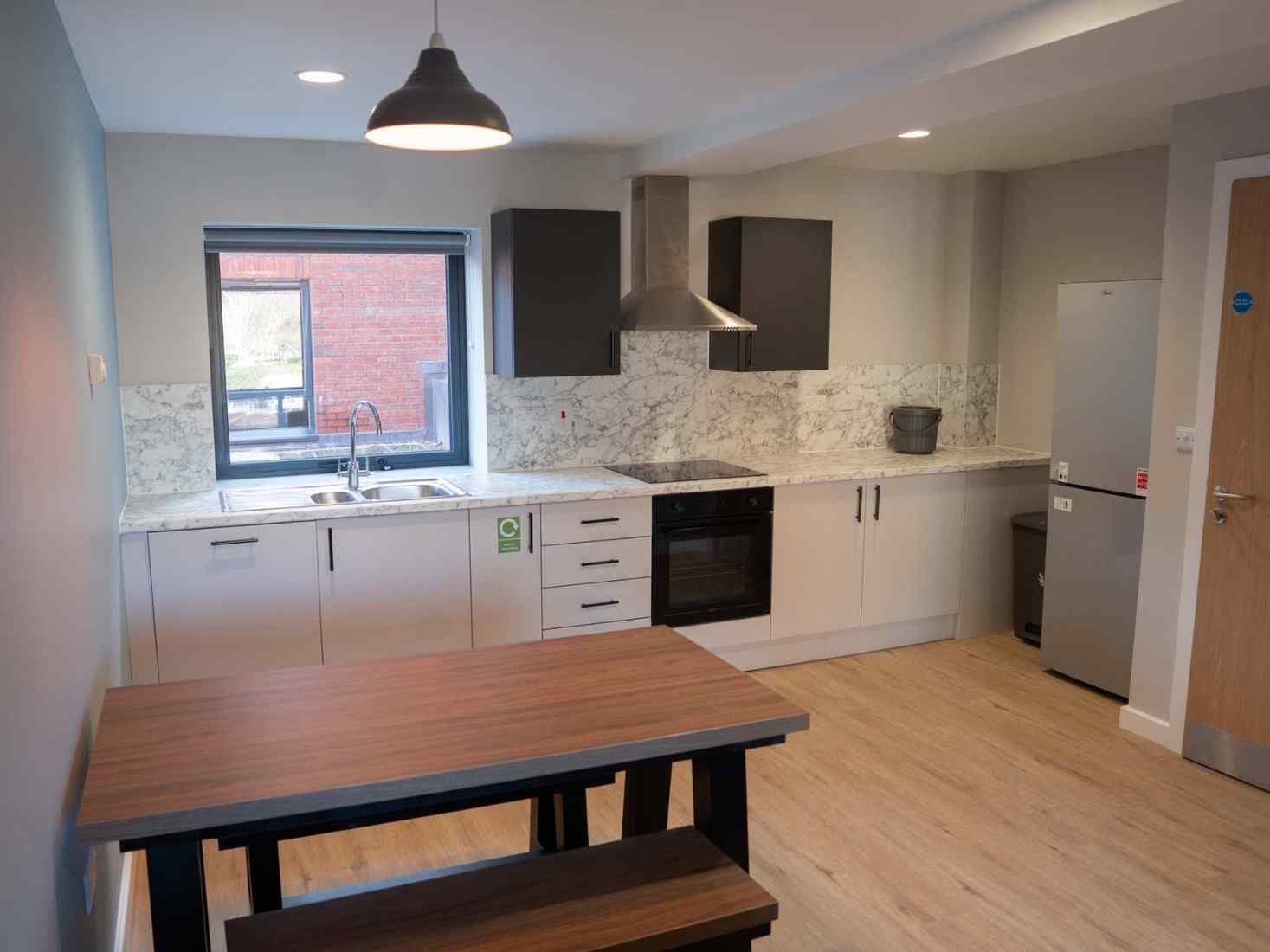 An image of a Kitchen in 49 Clarence Street accommodation, including a table, stove, window, and cupboards 
