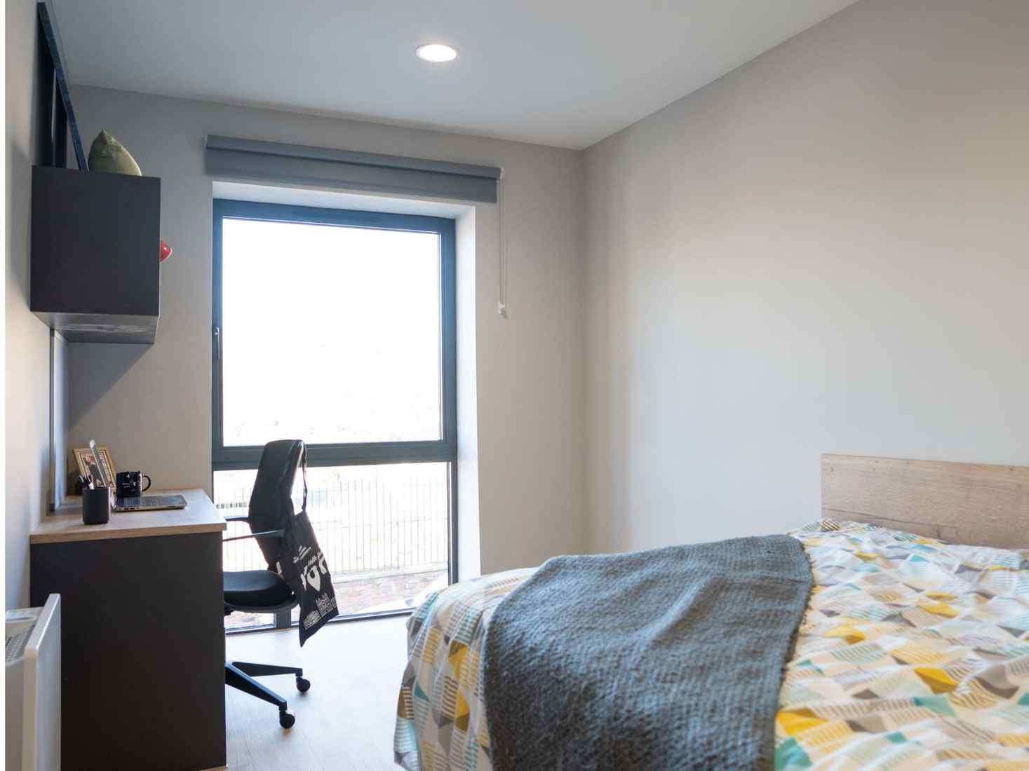 An image of a standard room in 79 Clarence Street accommodation, including single bed, desk and storage space 