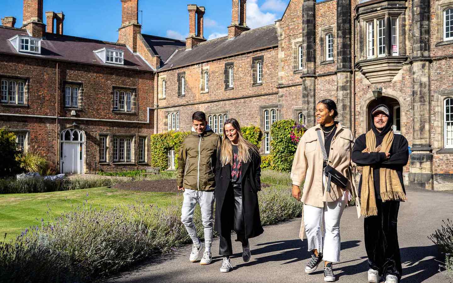 Four students walk together outside Lord Mayor's Walk on campus. 