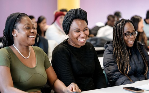 London Campus students sat at rows of desks in seminar. Students are laughing and smiling. 