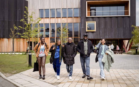 Five students walking together outside the Creative Centre on campus. 