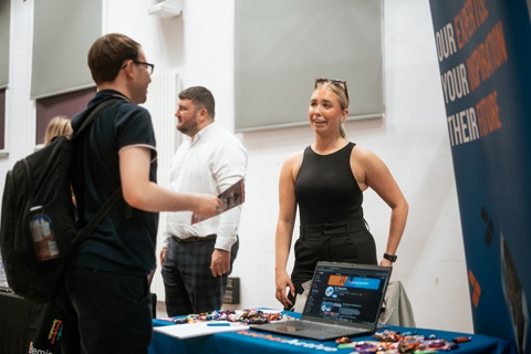 An employer speaking to students at a careers fair. 