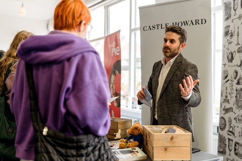 An employer speaking with students at a careers fair. 