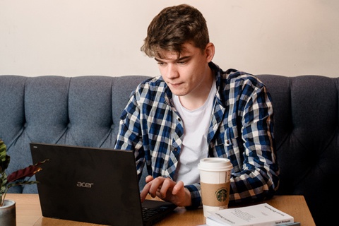 A student sitting at a table and using a laptop. 