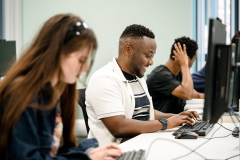 Students sitting at computer desks together and studying in the library. 