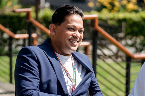 A staff member sitting outside on campus and smiling. 