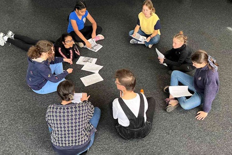 A group of people sitting in a circle together in discussion. 