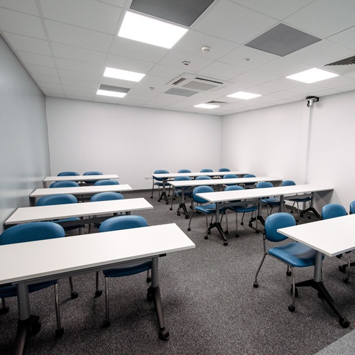 An empty learning room with chairs and tables laid out in rows. 