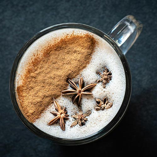 Cup of coffee from above with cinnamon and star anise on top 