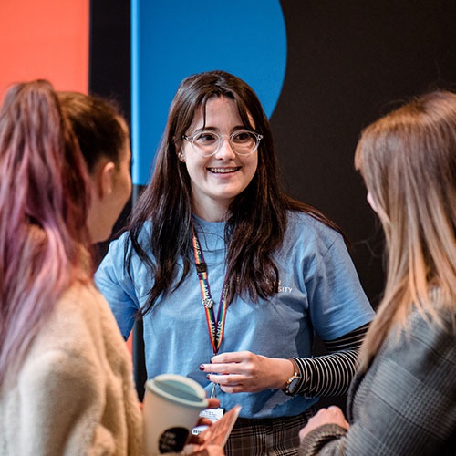 A member of staff talking to student visitors at an on-campus event. 