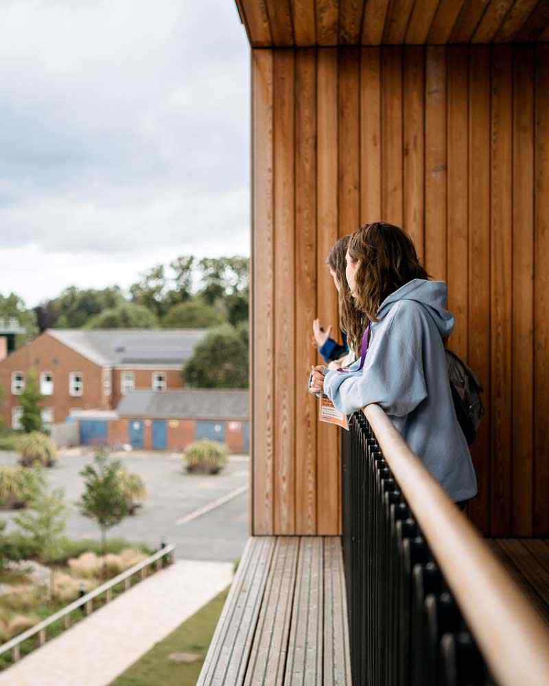 Two students looking out from the Creative Centre balcony. 